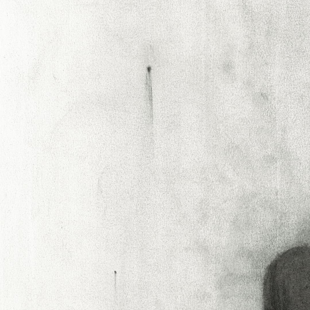 Mała ciemna zaokrąglona plama w prawej dolnej części jasnej kartki, z miękką pionową smugą poniżej i delikatną szarą poświatą. - zbliżenie/detal 3